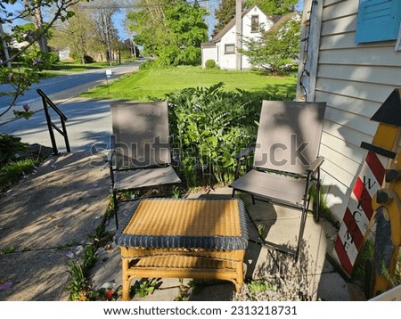 A few chairs and a table setup along side a home.