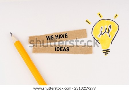 Business and education concept. A luminous light bulb is drawn on a white background, next to it lies a pencil and pieces of paper with the inscription - We Have Ideas
