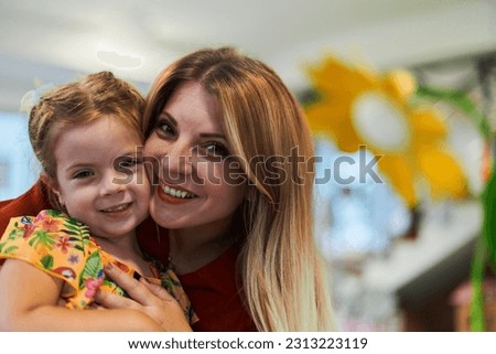A cute little girl kissing and hugs her mother in preschool