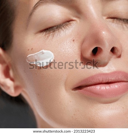 Skin treatment. Cream smear. Beauty close up portrait of young woman with a healthy glowing skin is applying a skincare product.  Royalty-Free Stock Photo #2313223423