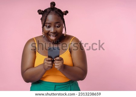 Overjoyed African American woman holding mobile phone shopping online with sales isolated on pink background. Excited African female using smartphone, reading good news, communication, win money 