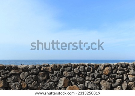 The blue sky that touches the horizon of the blue sea seen over the stone wall in Jeju Island Royalty-Free Stock Photo #2313250819