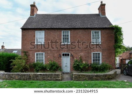 Detached double fronted 
red brick Victorian cottage with a green door in an English village Royalty-Free Stock Photo #2313264915