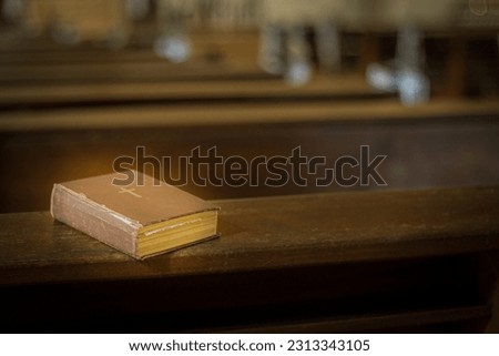Bible on the church bench. God's word in one little book. Soft selective focus. Artificially created grain for the picture