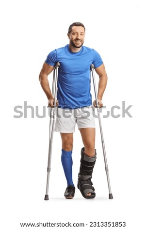 Full length portrait of a male athlete with crutches and a walking brace isolated on white background Royalty-Free Stock Photo #2313351853