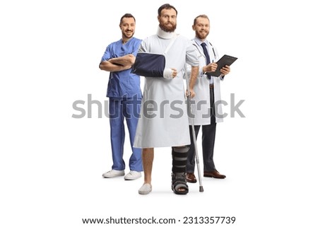 Team of doctors and a male patient with an orthopedic boot and cervical collar in a hospital gown isolated on white background
