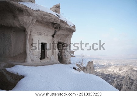 snowy hill cave houses in Uchisar city, Cappadocia, Turkey Royalty-Free Stock Photo #2313359253