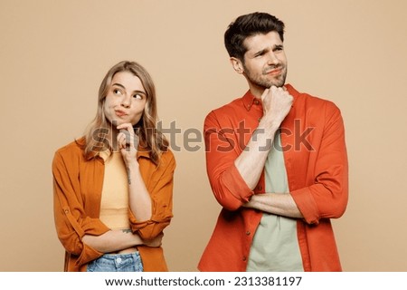 Young minded couple two friends family man woman wearing casual clothes put hand prop up on chin, lost in thought and conjectures together isolated on pastel plain light beige color background studio