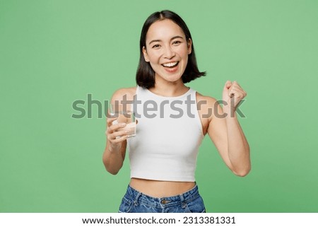 Young woman wear white clothes hold drink clear fresh pure still water from glass do winner gesture isolated on plain pastel light green background. Proper nutrition healthy fast food choice concept Royalty-Free Stock Photo #2313381331
