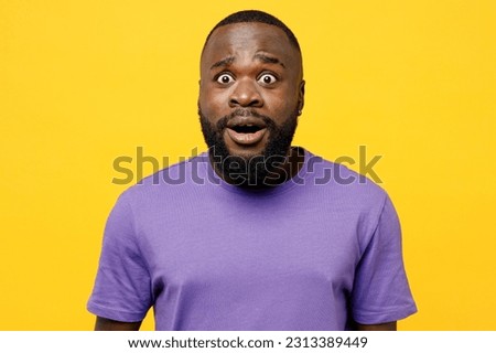 Young shocked scared sad man of African American ethnicity he wear casual clothes purple t-shirt look camera with opened mouth isolated on plain yellow background studio portrait. Lifestyle concept Royalty-Free Stock Photo #2313389449