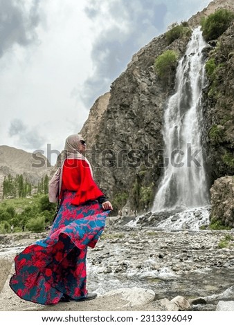 Portrait of beautiful young Muslim girl wearing Hijab and Jubah dress in outdoor scenes holding camera. Stylish Muslim female hijab fashion lifestyle portraiture concept.