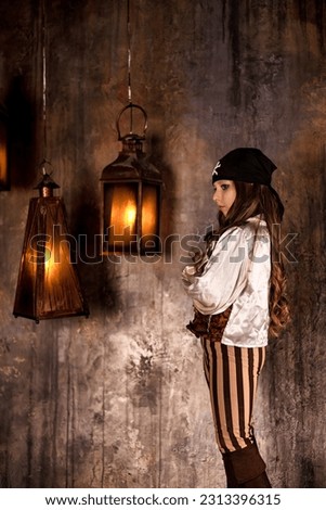 Portrait of little girl in pirate's image 7-8 year old posing at grey textured wall with lamps, pensive looking away. Actress child of pirate corsair. Theatre childhood concept. Copy ad text space