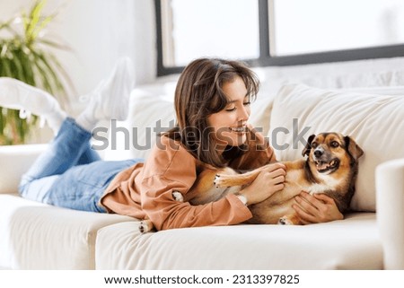 happy cheerful woman hugging her beloved pet dog at home on the couch Royalty-Free Stock Photo #2313397825