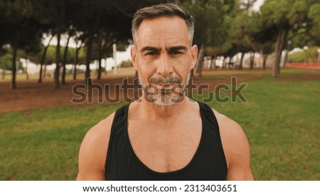 Close-up happy mature muscular man in sportswear looking at camera and smiling