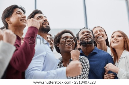 Group portrait of friends standing in office with fists clenched Royalty-Free Stock Photo #2313407523