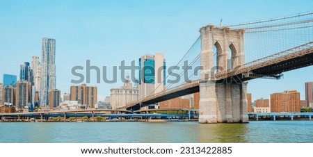 a view of the Brooklyn Bridge, above the East River, facing the Financial District and Lower Manhattan, in New York, United States, in a panoramic format to use as web banner or header