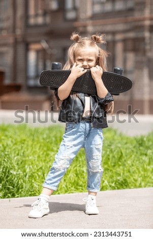 Stylish cool little girl child with skateboard outdoors on beautiful summer sunny day