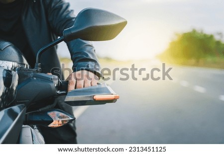 Hands of a motorcyclist on the handlebars on the road. Close up of hands of biker on the handlebars of a motorcycle outdoors. Motorbike speeding concept Royalty-Free Stock Photo #2313451125
