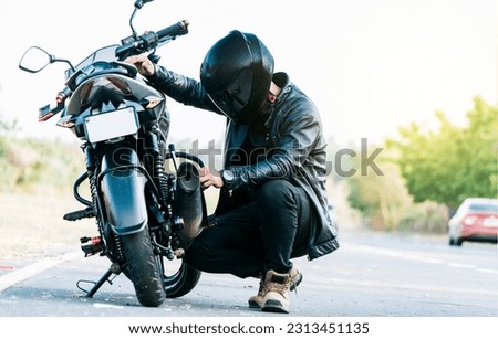 Motocyclist fixing the motorcycle on the road. Biker repairing motorcycle on the road, Man checking his motorcycle on the road Royalty-Free Stock Photo #2313451135