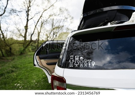 Happy family on board. Sticker on the back of car with roof box. Four kids.