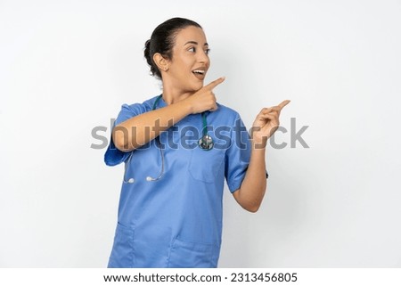Young doctor woman wearing blue uniform over isolated background smile excited directing fingers look empty space