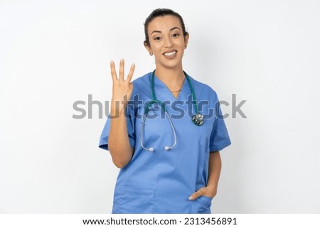 Young doctor woman wearing blue uniform over isolated background smiling and looking friendly, showing number three or third with hand forward, counting down