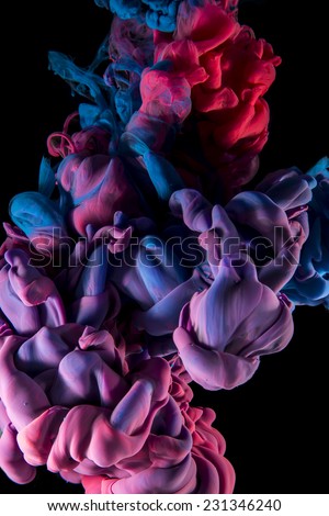 Color drop in water, photographed in motion. Ink swirling in water. Cloud of silky ink in water isolated on black background. Colorful ink in water, ink drop. Violet, blue, pink.