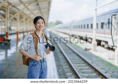 Asian teenage girl traveling using a camera take a photo to capture memories while waiting for a train at the station