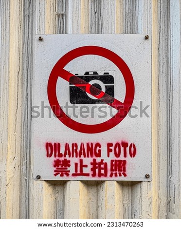 This is a sign that it is forbidden to take pictures in a certain area, displayed on a dusty iron wall with Chinese writing which means no photography is allowed. 