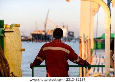 Seaman in red working overall and orange helmet on deck. Working at sea. Cargo vessel. Mooring operations. Able seaman. Royalty-Free Stock Photo #2313481189