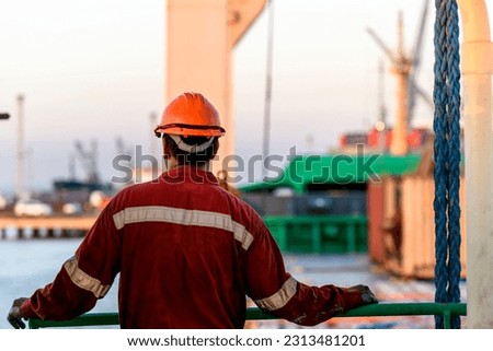 Seaman in red working overall and orange helmet on deck. Working at sea. Cargo vessel. Mooring operations. Able seaman. Royalty-Free Stock Photo #2313481201