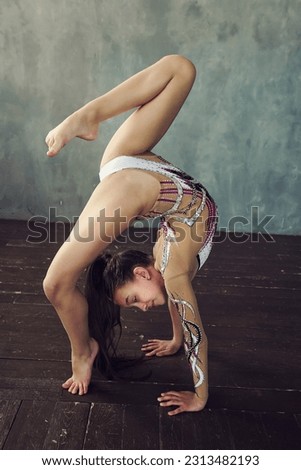 a young girl rhythmic gymnastics in a beautiful bodysuit does vertical splits