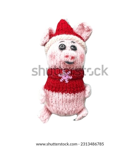 knitted toy pig in a red handmade jacket on a white background