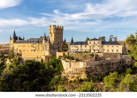 Alcazar of Segovia, Spain, medieval Spanish castle in Gothic architecture style on a hill with the Tower of John II of Castile, courtyard and Casa de la Quimica building, sunset.