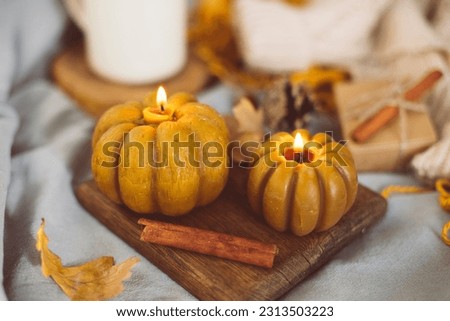 Burning candles shape of pumpkin and autumn decor on bed in bedroom