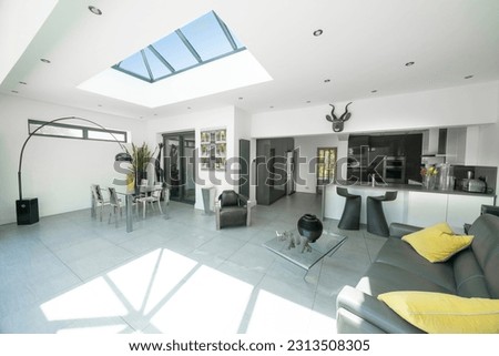 Interior of modern, bright, white and grey designer open plan kitchen diner and lounge, with skylight roof lantern. Royalty-Free Stock Photo #2313508305