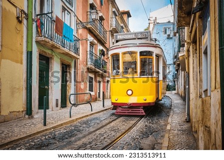 Famous vintage yellow tram 28 in the narrow streets of Alfama district in Lisbon, Portugal - symbol of Lisbon, famous popular travel destination and tourist attraction Royalty-Free Stock Photo #2313513911