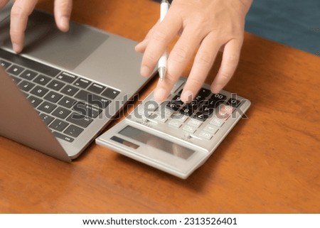 The dedicated businessman is multitasking with utmost precision, effortlessly maneuvering his laptop, mobile phone, and calculator to streamline his business operations and make informed decisions. Royalty-Free Stock Photo #2313526401