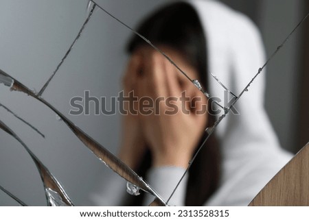Woman covering face with hands near broken mirror. Mental problems Royalty-Free Stock Photo #2313528315