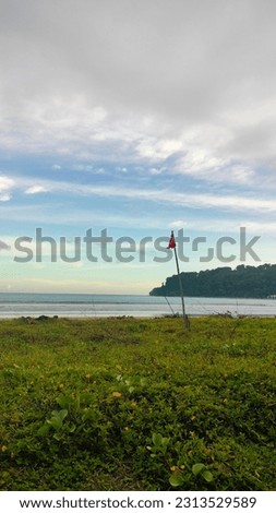 Pictures of landscape portraits, beaches in Indonesia, where there are waves, sea water, white sand, hills, flags marking the reach of the waves, and a charming morning sky