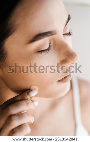 Applying acne round patch on cheek of girl close-up. Young woman using acne patches for treatment of pimple and rosacea. Facial rejuvenation cleansing cosmetology Royalty-Free Stock Photo #2313542841