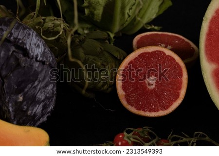 Various fruits and vegetables assorted over a dark black background (apple, pineapple, watermelon, grapefruit, tomatoes, lettuce)