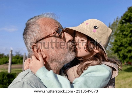 Emotional mature father embracing and kissing little daughter