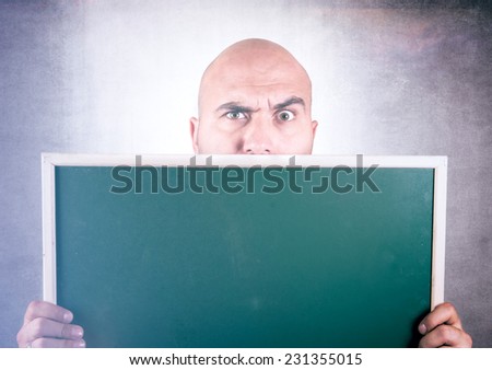 Bold man holding blank chalk board in his hands