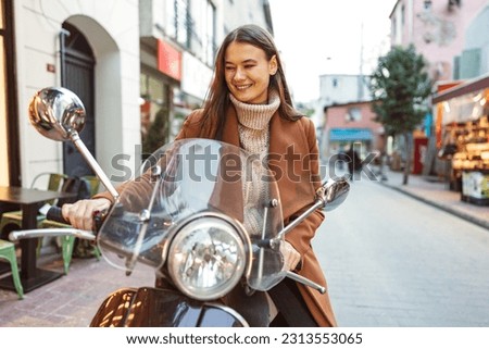Portrait of attractive young cheerful woman riding moped scooter Royalty-Free Stock Photo #2313553065