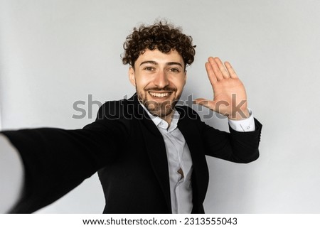 Image of successful man 30s in business suit gesturing hand aside while taking selfie photo isolated over gray background