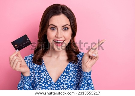 Photo of astonished crazy woman wear blue dress indicating at sale empty space hands hold credit card isolated on pink color background