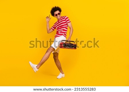 Full length photo of cool funky guy dressed red t-shirt dark glasses dancing enjoying boom box songs isolated yellow color background