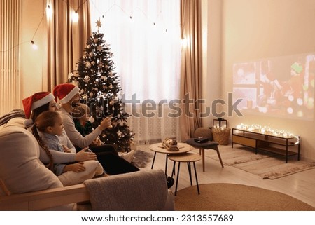 Family watching Christmas movie via video projector in cosy room. Winter holidays atmosphere