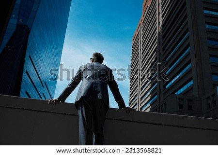 Business, man and thinking at city on rooftop about career or future with goal in company. Professional, person and skyscraper on roof is standing with vision or hope for decision as leader at work. Royalty-Free Stock Photo #2313568821